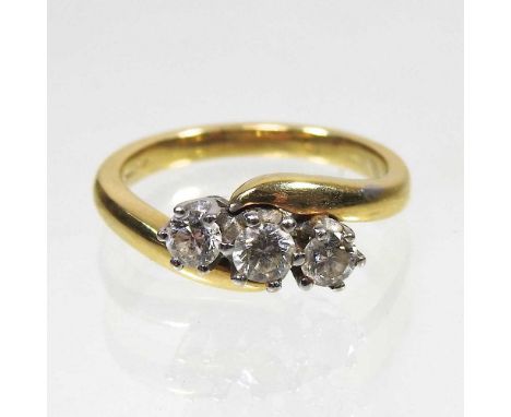 An 18 carat gold three stone diamond ring, of crossover design, approximately 0.5 carats gross, size L, 4.8g