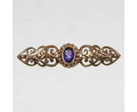 A 9 carat gold and amethyst set brooch, of Victorian design, with a scrolled surround, 6.3G, 5cm wide