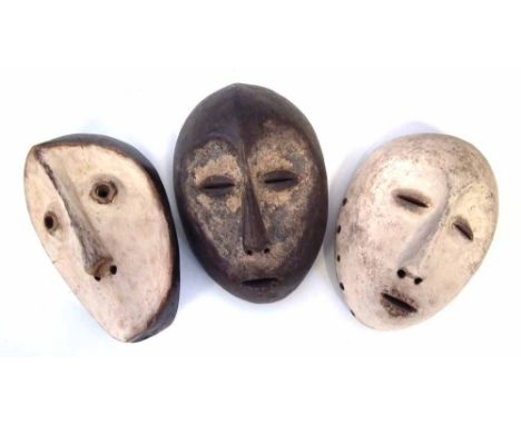 Three Lega masks carved with handles to the reverse, 25cm high       All lots in this Tribal and African Art Sale are sold su