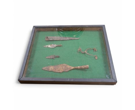 A display cabinet with a collection of antiquities comprising; medieval spur, spear and arrow heads, 53cm high. Condition - f