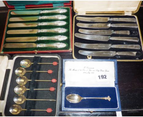 Two cased sets of silver-handled tea knives, a silver commemorative spoon, and a set of EPNS coffee bean spoons