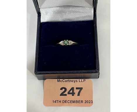 A 9ct three stone emerald and diamond ring. 1.3g gross. Size K.