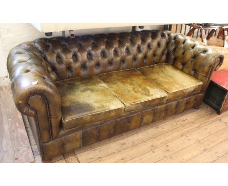 A three seater Chesterfield sofa in aged dark green leather with button back