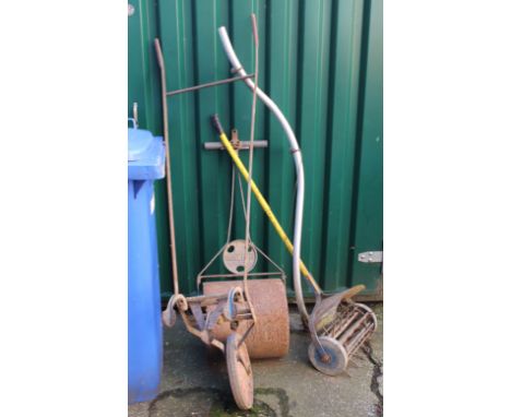 A vintage scythe, concrete garden roller and plough