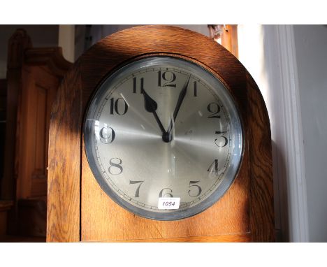 A 1920's oak long case clock with round silvered chapter ring and chiming music