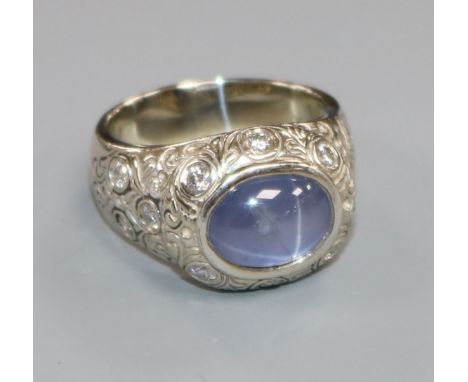 An ornate white metal, cabochon star sapphire and diamond set dress ring, size Q/R.