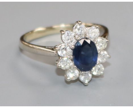 A modern 18ct white gold, sapphire and diamond oval flower head cluster ring, size R/S.