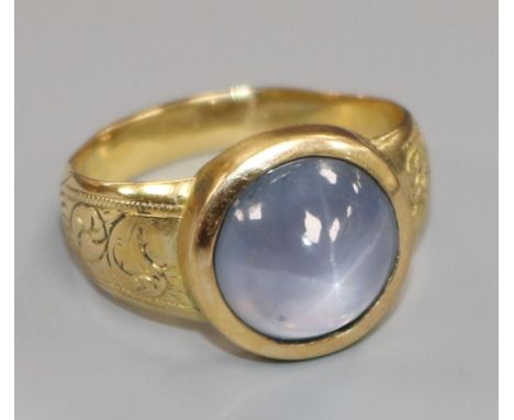 An engraved yellow metal and cabochon star sapphire ring, size O.