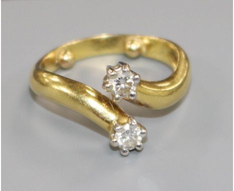 A yellow metal and two stone diamond crossover ring, size K/L.