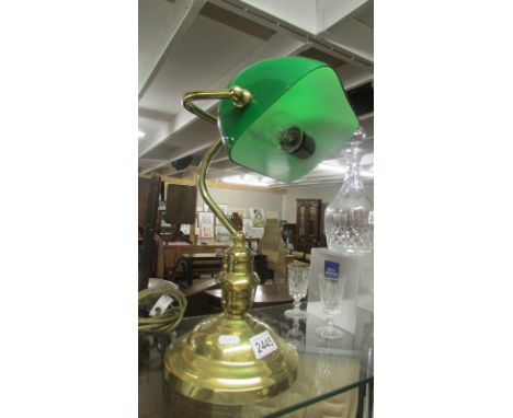 A brass bankers lamp with green glass shade.