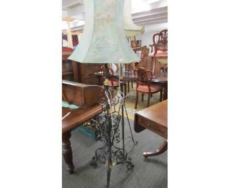 An ornate wrought iron and brass standard lamp with shade.