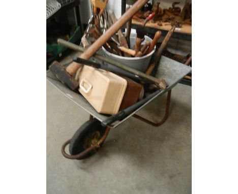 A galvanised wheel barrow with garden tools.