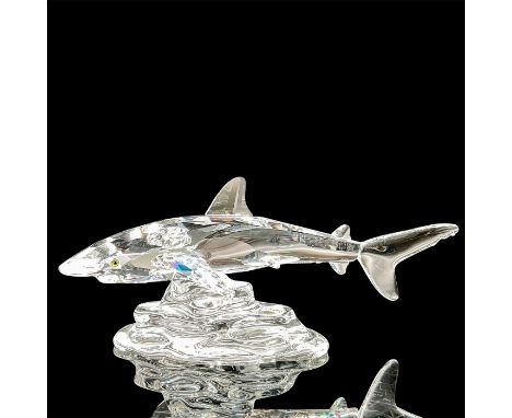 A clear faceted shark swimming over a clear rocky base. Swarovski mark. This item has its original box: 6"W x 4.75"H Artist: 