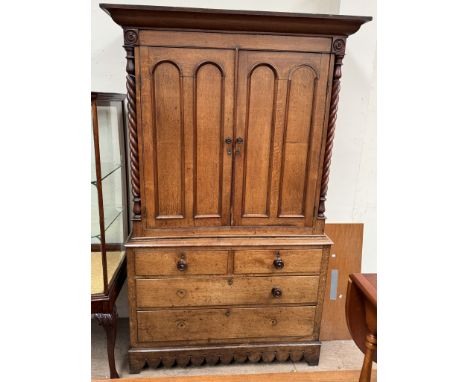 A 19th century oak linen press with a moulded cornice above a pair of panelled doors enclosed between rope twist columns, the