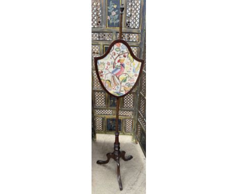 A Victorian mahogany pole screen with a shield shaped screen decorated with a parrot amongst flowers on a turned column and t