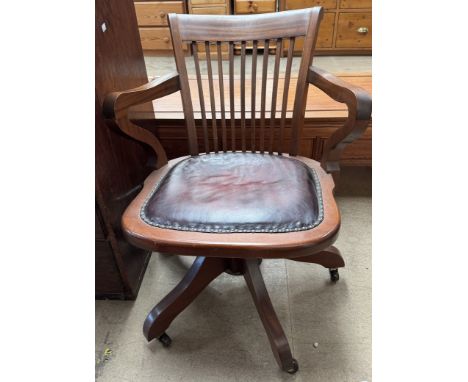 An office chair with a stick back above a pad seat on a rotating base and four legs with casters