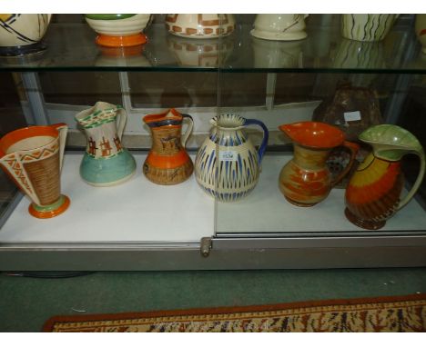Six colourful Myott Jugs, various patterns including blue jug with twisted handle, etc.