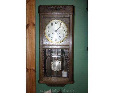 An Oak cased three train movement Wall Clock having bevelled glass revealing the pendulum and with string pull repeating mech