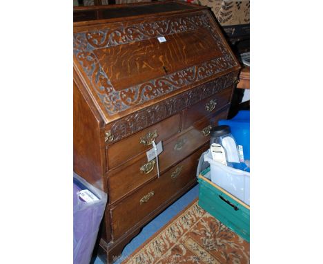 A carved detail Oak fall-front Bureau, the interior with a storage well, pigeon holes and drawers and having two long and two