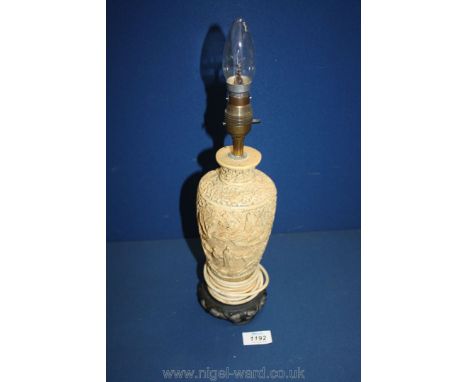 An oriental style table lamp with carved decoration of figures, flowers, etc.,