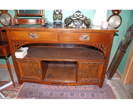 An Arts and Crafts Oak sideboard having a lower aperture flanked by copper hinged cupboards, the full width recess over with 