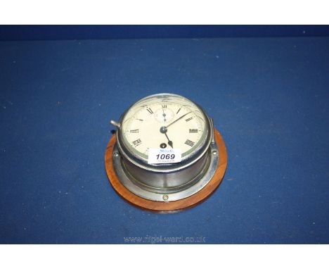 A small circular, white metal ship's clock.