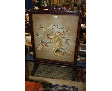 A good Mahogany framed Firescreen, the panel decorated with a needleworked depiction of a peacock perched in a flowering shru