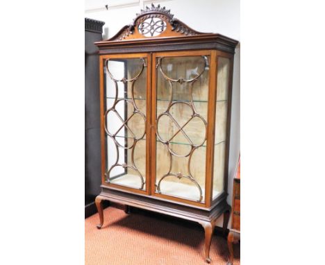 A late Victorian mahogany display cabinet, the pierced arched cornice heavily carved with scrolls and an open lattice work, w