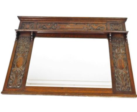 An early 20thC oak Arts &amp; Crafts over mantel mirror, of rectangular form with carved frieze above plain shelf, the plain 