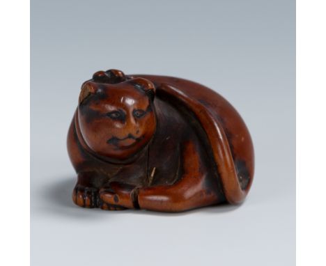 AN OLD WOOD NETSUKE OF A RECUMBENT CATUnsignedJapan, 18th century, Edo period (1615-1868)An appealingly worn, tactile, and ch