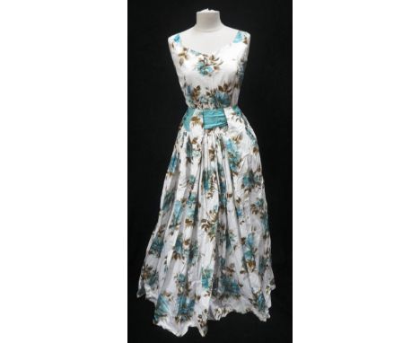 A 1950S LADIES EVENING DRESS decorated with blue flowers and foliage with deep ribbon belt tie and long skirt