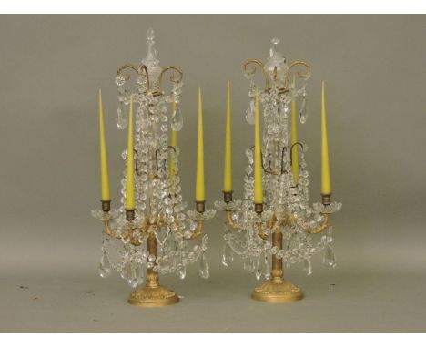 A pair of late 19th/early 20th century four light candelabra, with cut glass drops and gilt metal bases
