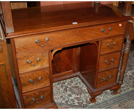 A Georgian style mahogany and flame mahogany kneehole writing desk, having arrangement of seven drawers and kneehole cupboard