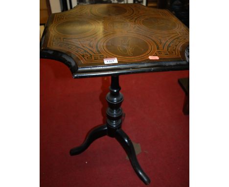 A 19th century ebonised hinge-top pedestal tripod table, the top decorated with Roman centurions 