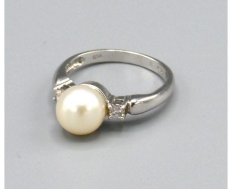 A 18ct White Gold Pearl and Diamond Ring set with a large central pearl surrounded by two diamonds within a pierced setting, 