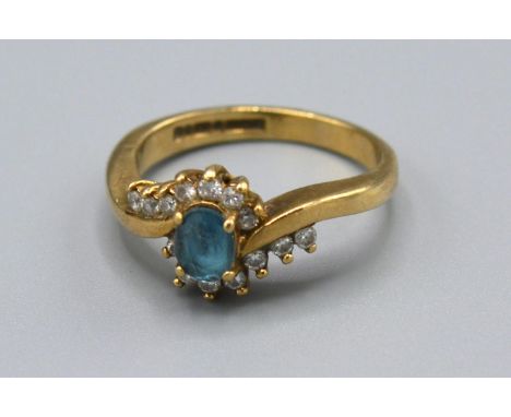 A 9ct Yellow Gold Diamond Set Ring with Central Blue Stone surround by diamonds in a crossover setting, Size J, 2.6 grams 