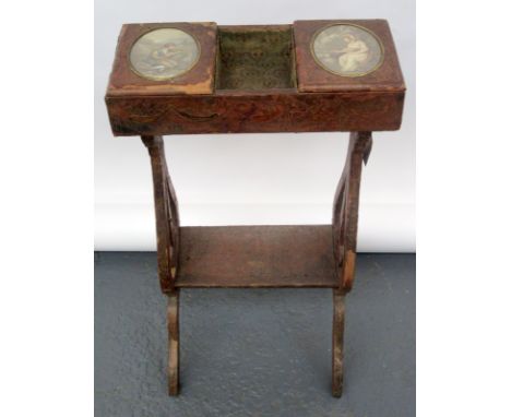 A 19th century leather clad sewing table with a central well flanked by hinged lids set with oval prints of a shepherd and sh