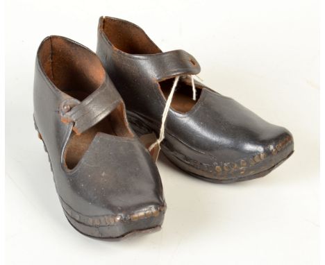 A pair of 19th century children's leather clogs with steel mounted wooden soles and single button fastening strap, possibly L