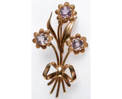 A 9ct. gold brooch, cast as three flowers tied together with a ribbon, a rose cut amethyst to the centre of each flower, leng