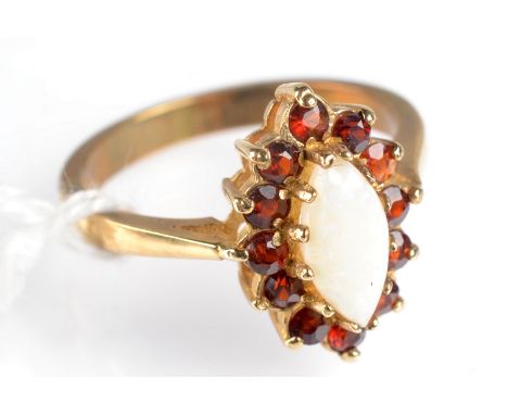 A 9ct. gold ring set a lozenge shape opal surrounded by garnets.