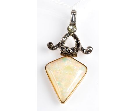 A kite shaped opal set beneath a scrolling diamond mount as a pendant with bagette diamond suspension loop.