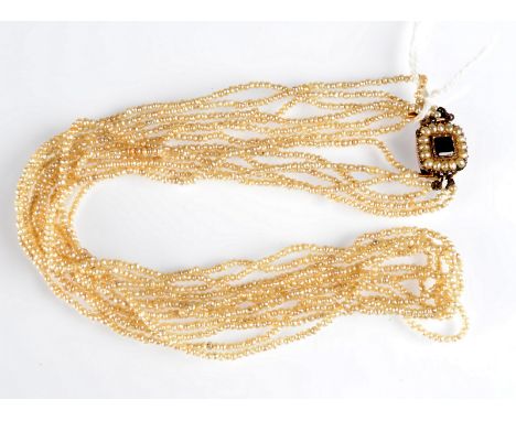 A seed pearl six strand necklace, the fine gold clasp set a central red stone within pearls.