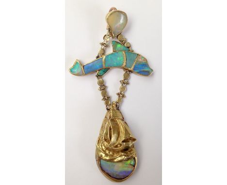 An Arts and Crafts post war pendant in gold coloured metal, set with opals in the form of a dolphin leaping over a sailing sh