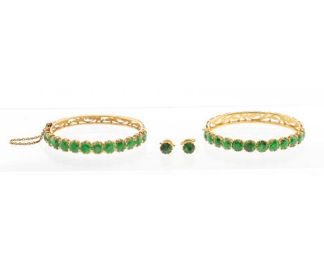 A pair of emerald and high carat yellow gold hinged bracelets, each claw set twelve round faceted emeralds to the front, widt