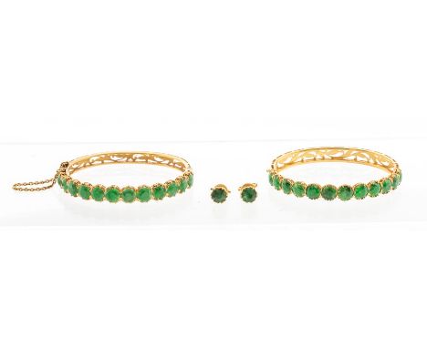 A pair of emerald and high carat yellow gold hinged bracelets, each claw set twelve round faceted emeralds to the front, widt