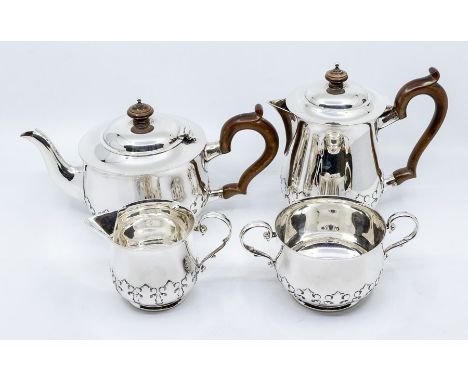 A George V silver four piece tea service with stylized leafage raised frieze, turned wooden scroll handles and finials, Londo
