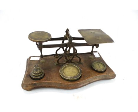 A vintage set of postage letter scales with weights. Brass balance scales mounted on oak plinth on bun feet with six assorted