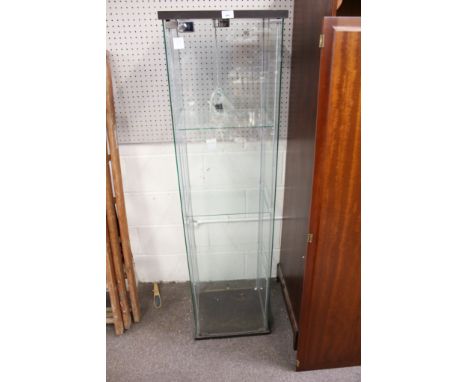 A contemporary glass display cabinet. Three shelved with a hinged door to the front and an electric light fitted to the top, 