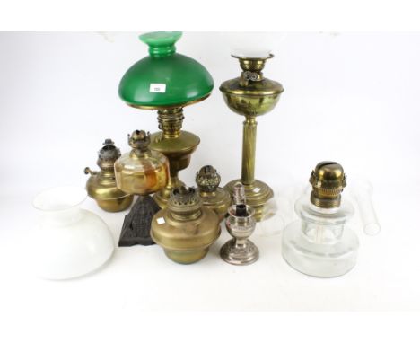 A collection of vintage brass oil lamps and accessories. Of various designs; one lamp with moulded details and an orange glas