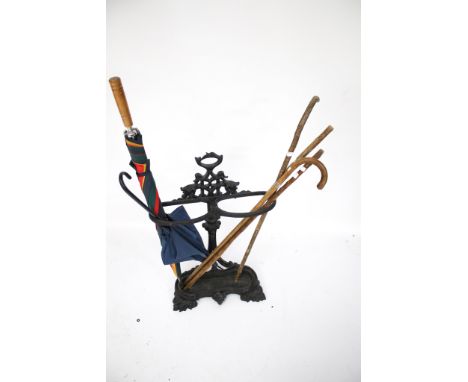 A Victorian cast metal stick and umbrella stand together with an assortment of sticks. The stand painted black and with mould